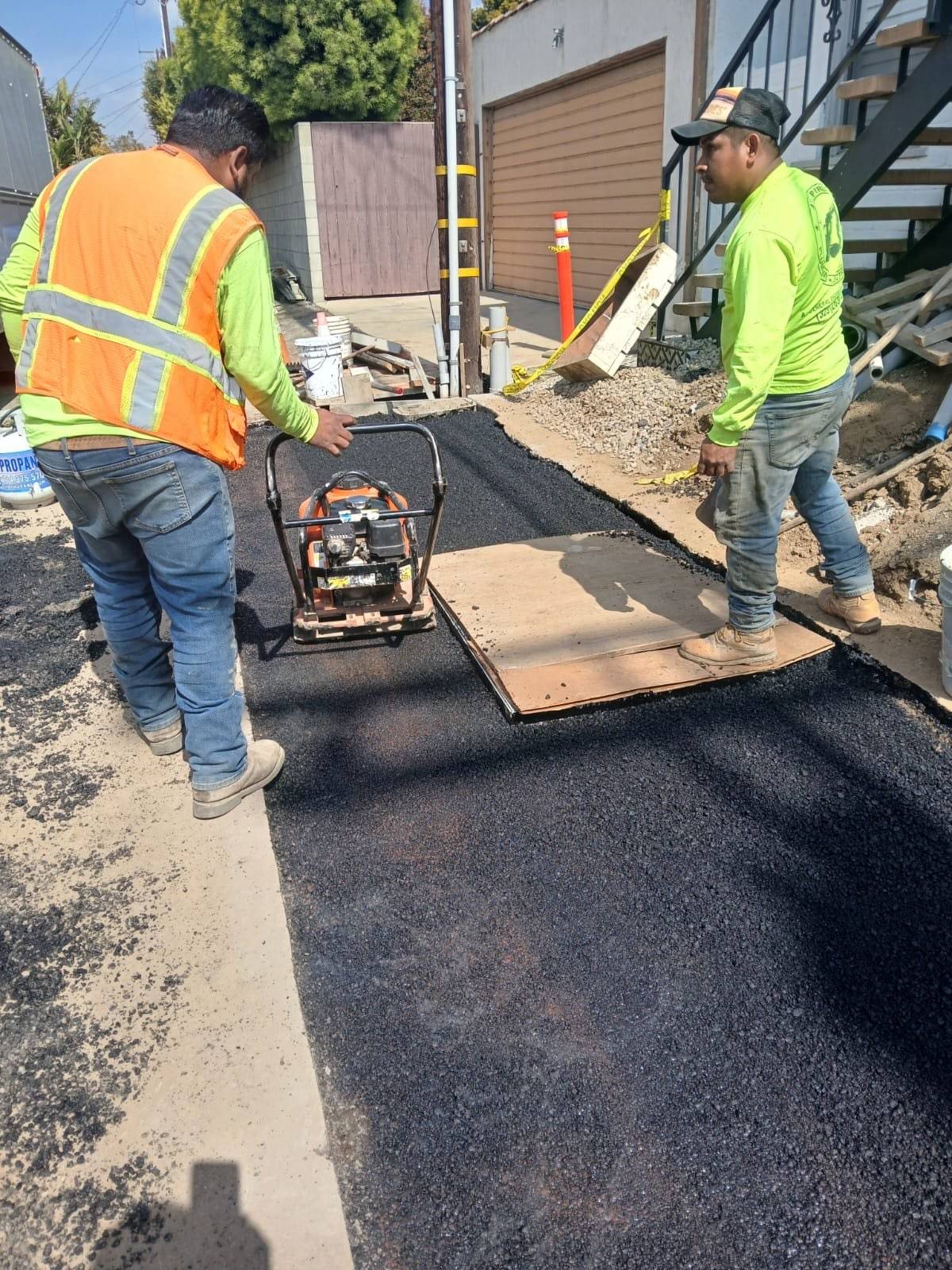 Crew compacting fresh asphalt after the trench was closed