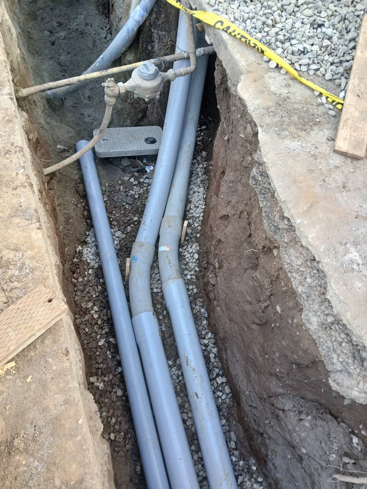 Three new PVC laterals in crushed rock next to a water meter