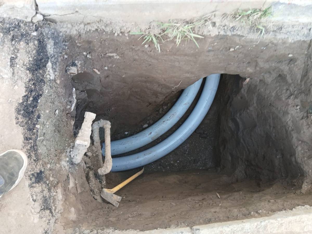 Swept PVC pipes laid in an excavated pit with old fittings still in the dirt